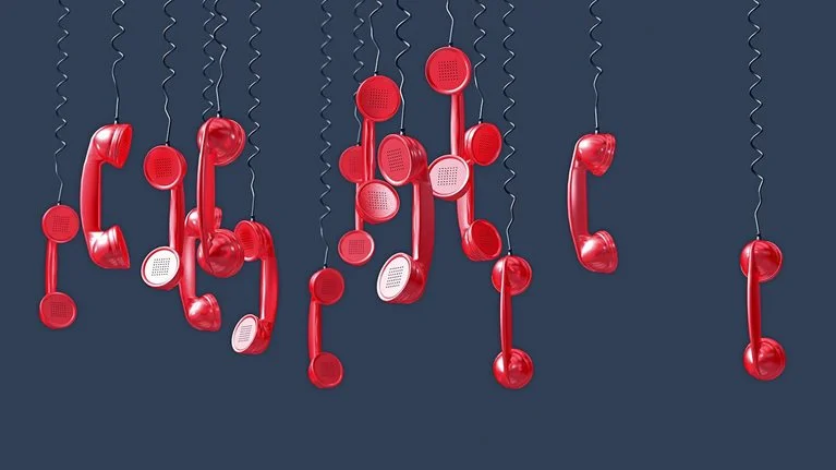 Image of numerous red phones hanging upside down by their cords.