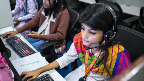 Bloomberg via Getty Images Employees wear headsets while working at the Avise Techno Solutions LLP call center in Kolkata, India, on Sunday, Dec. 24, 2017.